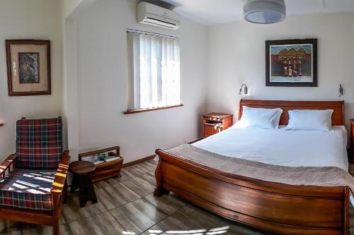 een slaapkamer met een groot bed en een stoel bij Mtunzini BnB in Mtunzini