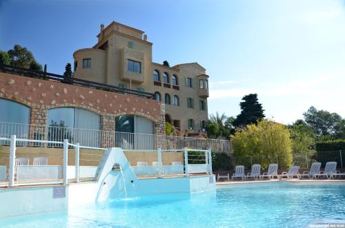 un toboggan dans une piscine en face d'un bâtiment dans l'établissement Village Vacances Lou Castelet, à Théoule-sur-Mer