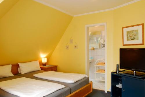 a small room with two beds and a television at Hotel am Südwäldchen in Westerland (Sylt)