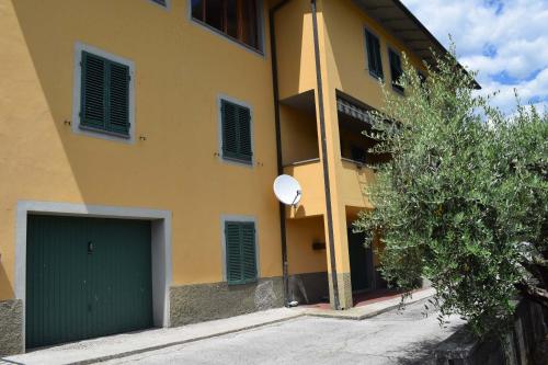 a yellow building with a green garage in front of it at Casa Daniela in Bagni di Lucca