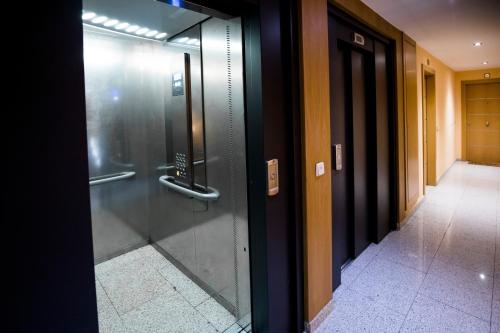 une porte d'ascenseur en verre dans un immeuble avec couloir dans l'établissement Confort Escaldes, à Andorre-la-Vieille