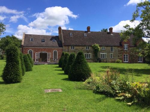 a large brick building with a yard with bushes at The Old Rectory,Nr Silverstone in Towcester