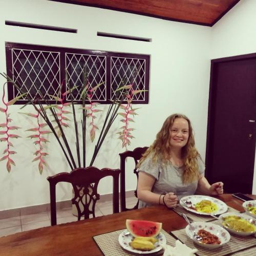 a woman sitting at a table with a plate of food at Old Parkland Hostel in Galle
