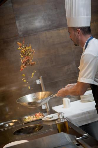 a chef preparing food in a restaurant kitchen at MenDan Magic Spa & Wellness Hotel in Zalakaros