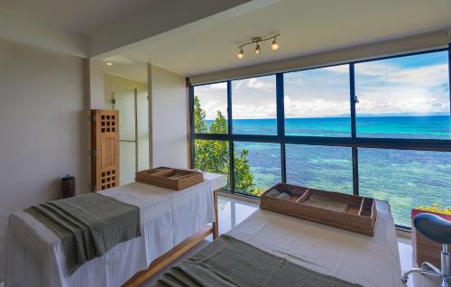 two beds in a room with a large window at Coco de Mer Hotel and Black Parrot Suites in Grand'Anse Praslin