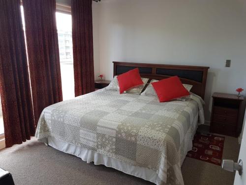 a bedroom with a bed with red pillows on it at Departamento Alejandra in El Tabo