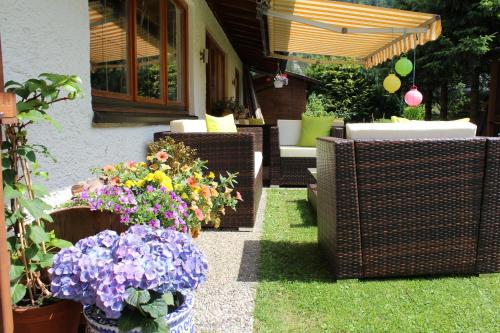 a patio with chairs and flowers in a yard at Haus Guentli in Mittelberg