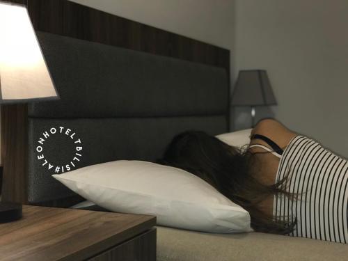 Kobieta leżąca na łóżku z głową na poduszce w obiekcie Aleon Hotel w mieście Tbilisi City