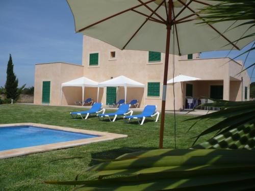 a pool with chairs and an umbrella next to a building at Finca Sa Carrotja in Porto Cristo