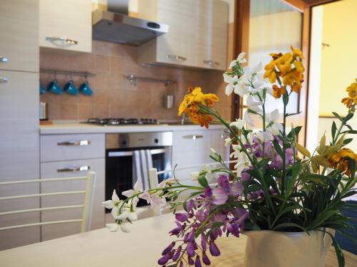un vase de fleurs sur une table dans une cuisine dans l'établissement LA BRIGATA APARTMENTS Yellow House, à Cavallino-Treporti