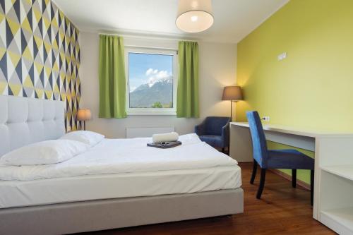 a bedroom with a bed, desk, chair, and lamp at Hostel Marmota in Innsbruck
