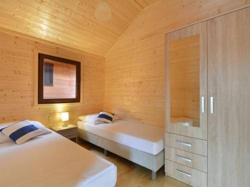 a bedroom with two beds in a wooden room at Domki Korsarz Gaski in Gąski