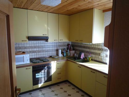 uma cozinha com armários amarelos, um fogão e um micro-ondas em FeWo Ortloff em Füssen