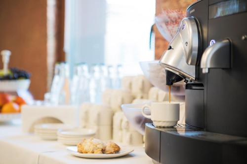 a coffee maker pouring coffee into a cup on a counter at Hotel Internazionale Bellinzona in Bellinzona