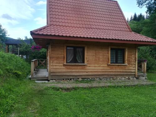 una pequeña casa de madera con techo rojo en Magellan Domki en Cisna