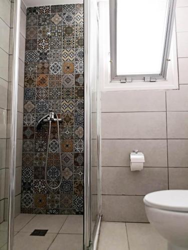a bathroom with a shower with a toilet and a window at Cheerful Apartment in Nicosia in Yukarı Lakatamya
