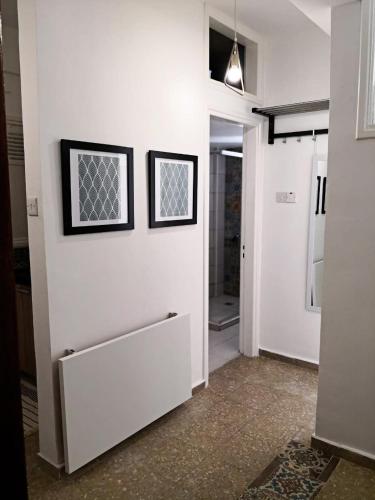 a hallway with a white wall with two pictures on it at Cheerful Apartment in Nicosia in Yukarı Lakatamya