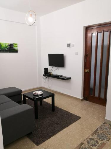 a living room with a couch and a table and a tv at Cheerful Apartment in Nicosia in Yukarı Lakatamya