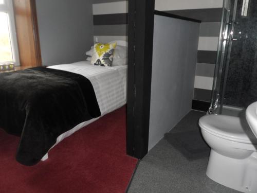a small bathroom with a bed and a toilet at Midtown Farm Bed & Breakfast in Easton