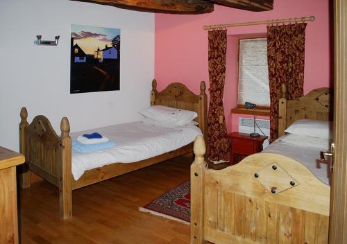 deux lits dans une chambre aux murs roses dans l'établissement Val Rive - Rose Cottage, à Dinan
