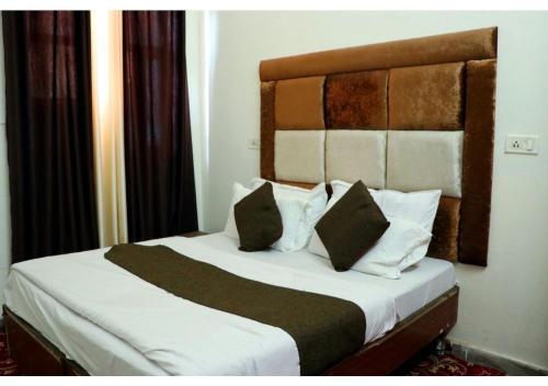 a bedroom with a bed with white sheets and pillows at Inderlok Hotel in Chandīgarh