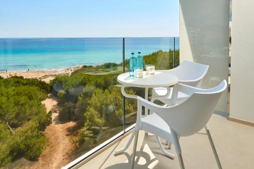 
a white chair sitting on top of a wooden deck next to a beach at Hipotels Bahia Cala Millor in Cala Millor
