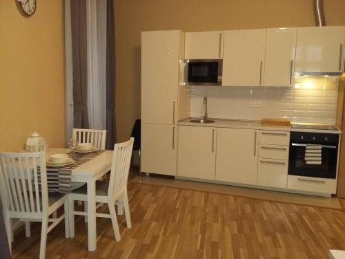 プラハにあるApartment Vltavska Fの白いキャビネット、テーブルと椅子付きのキッチンが備わります。