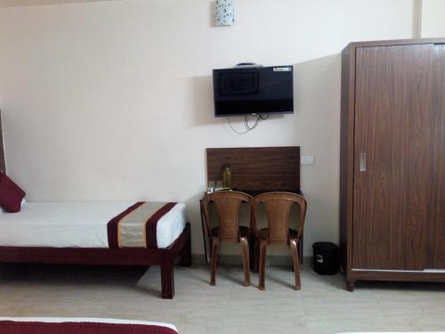 a bedroom with a bed and a table and two chairs at Hotel Lovely Nest in Coimbatore