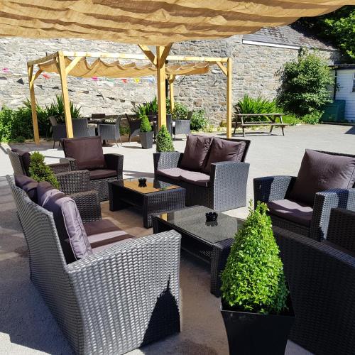 a group of wicker chairs and tables under an umbrella at The Lamb and Flag Inn in Rhayader