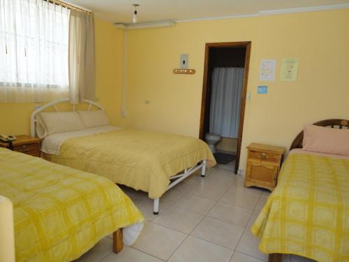 twee bedden in een kamer met gele muren bij Hostal El Sol de Cayambe in Cayambe