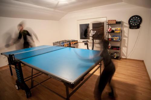 a ping pong table in a room with two people at House Utrinek with free play room, jacuzzy and garage in Podbrdo