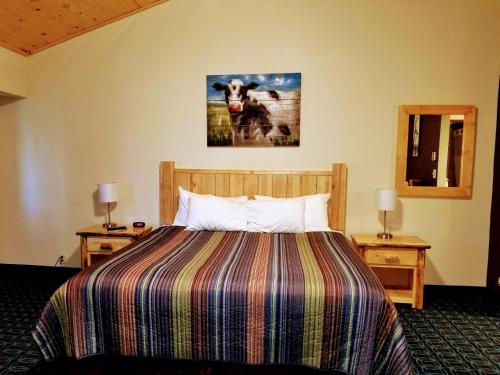 a hotel room with a bed and a picture of a cow at Round Barn Lodge in Spring Green