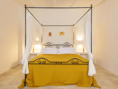 a bedroom with a canopy bed with a yellow blanket at Masseria Marzalossa in Fasano