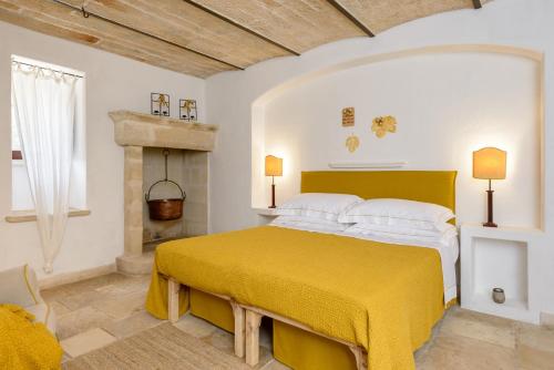 a bedroom with a yellow bed and a fireplace at Masseria Marzalossa in Fasano