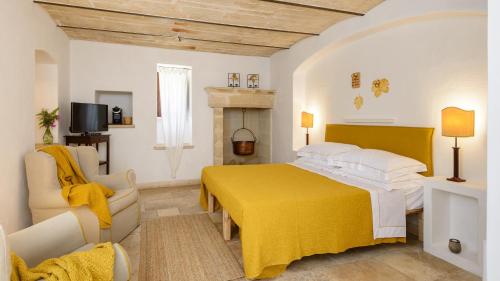 a bedroom with a yellow bed and a fireplace at Masseria Marzalossa in Fasano