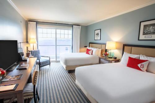 a hotel room with two beds and a desk at Beauport Hotel Gloucester in Gloucester