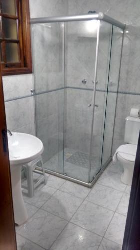 a bathroom with a shower with a toilet and a sink at Pousada AlpenRose in Campos do Jordão