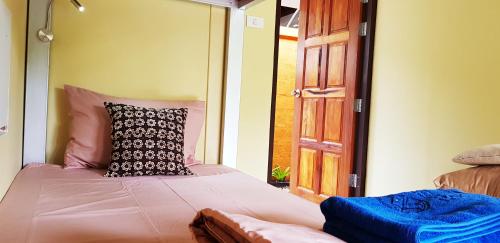 a bedroom with a bed with a pillow on it at Baan Hinlad Home and Hostel in Lipa Noi