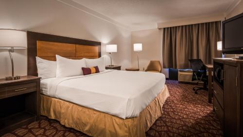 フォートマイヤーズにあるBest Western Airport Inn Fort Myersの大きなベッドとデスクが備わるホテルルームです。