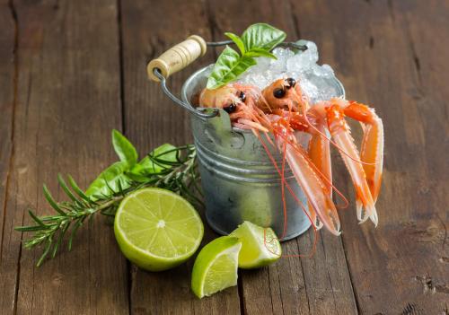a jar filled with shrimp and vegetables on a wooden table at Brattvåg Fjordhotell in Brattvåg