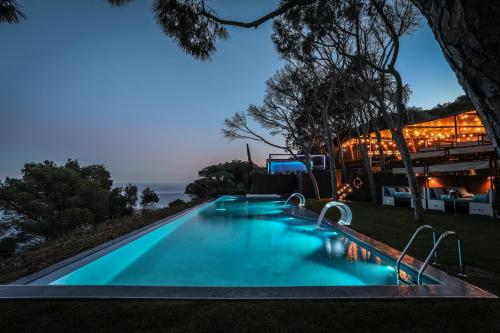 a swimming pool in front of a building with the ocean at Alàbriga Hotel GL in S'Agaro