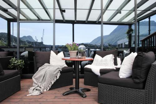 a patio with chairs and a table with a view of mountains at Brattvåg Fjordhotell in Brattvåg