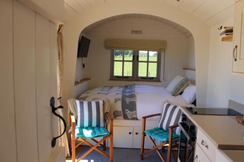 a small bedroom with a bed and two chairs at Fair Farm Hideaway in Waltham on the Wolds
