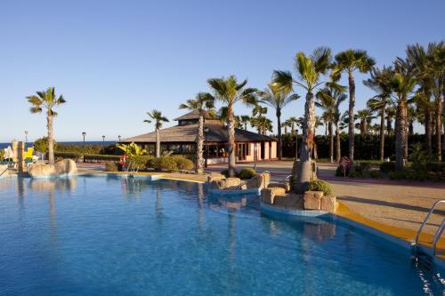 una piscina con palmeras en un complejo en Playazimbali, en Vera