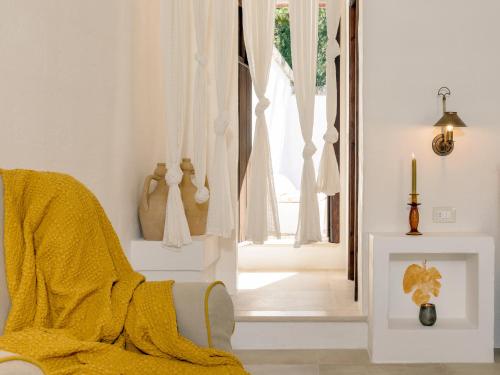 a living room with a yellow blanket on a chair and a window at Masseria Marzalossa in Fasano