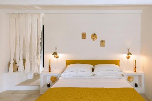 a white bedroom with a bed with a yellow blanket at Masseria Marzalossa in Fasano