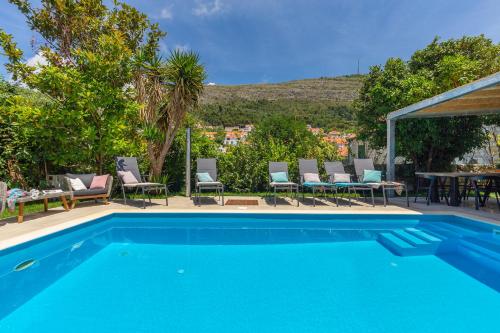 a swimming pool with chairs and a table at Villa Hedera II in Dubrovnik