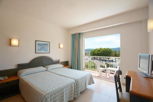 a bedroom with a bed and a balcony with a television at Invisa Hotel Es Pla - Adults Only in San Antonio