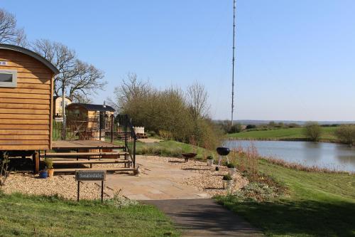a building next to a river next to a lake at Fair Farm Hideaway in Waltham on the Wolds