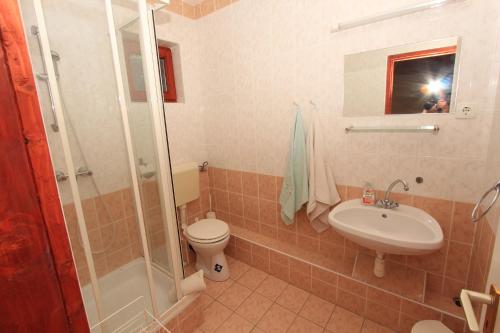 uma casa de banho com um WC, um lavatório e um chuveiro em Ariel apartmanok em Siófok